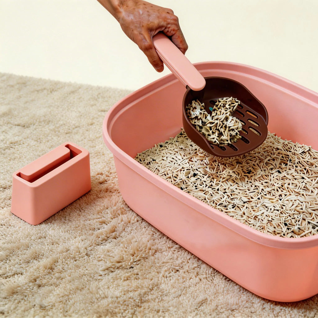 Hand scooping clumping cat litter from pink litter box on beige carpet