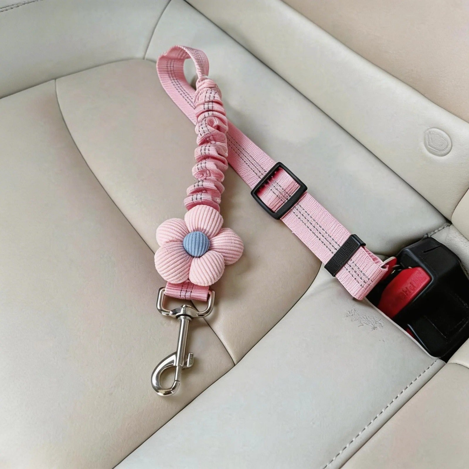 Pink pet seat belt with flower decoration on beige car seat, dog safety accessory